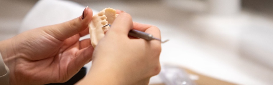 Photo of hands working on tooth mold. 