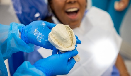 Student showing an alginate impression with the fellow looking on. 