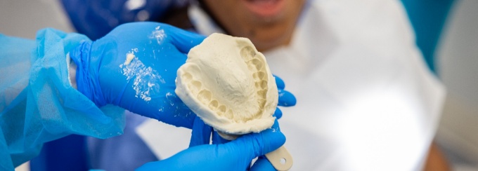 Student showing an alginate impression with the fellow looking on. 
