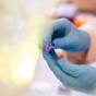 Gloved hands handle a lab specimen. 