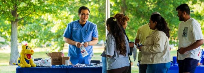 A UB dental student greets a member of the community during an outreach event in July 2026. 