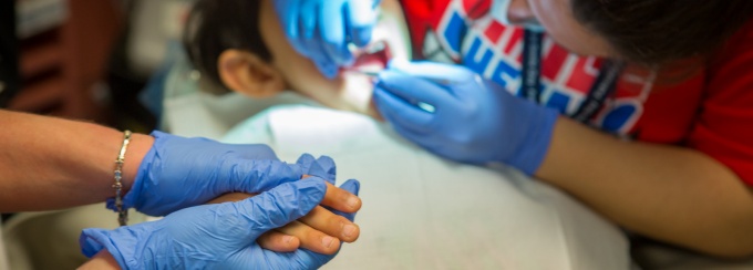 Dentists provide care to a pediatric patient. 