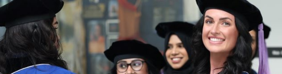 dental students in graduation robes and gowns standing in a large hallway.