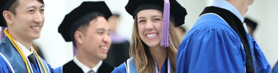 Students in graduation robes and caps smiling. 