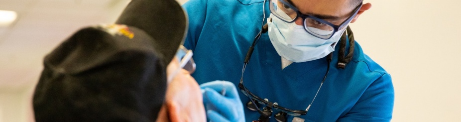 UB SDM student cleaning a person's teeth.