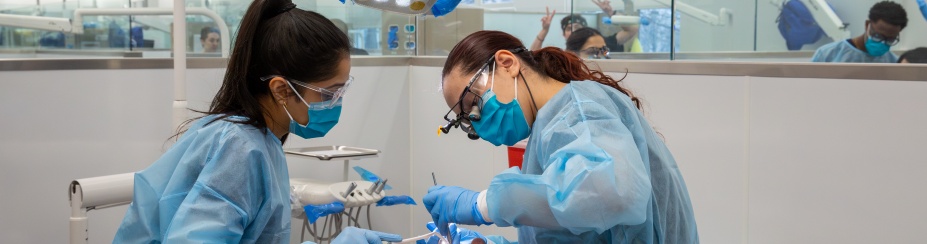 two students working on patient in clinic.