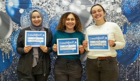 Three dental students standing while holding signage of where they are going to be attending their residency programs. 