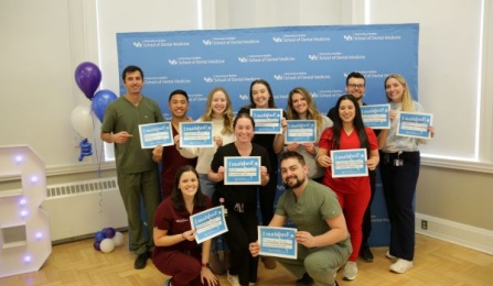 dental students standing while holding signage of where they are going to be attending their residency programs. 