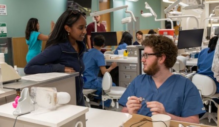 Two dental students working on a table bench in our pre clinical simulation center. 