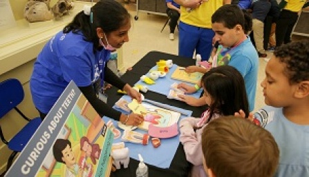 Dental student working with three kids to promote good oral health care. 