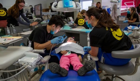 two students working on a pediatric patient in the clinic. 