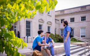 Three students chat outside on the steps of Harriman Hall. 