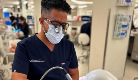 dental student sitting on chari working on mannequin in the preclinic simulation lab. 