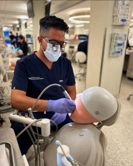 dental student sitting on chari working on mannequin in the preclinic simulation lab. 
