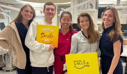 group of dental students standing holding signs in preclinic simulation lab. 