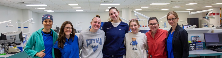 current dental students, faculty, and staff in the dental clinic wearing scrubs. 