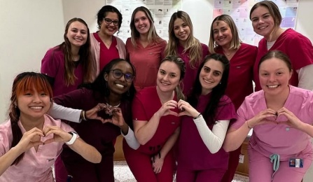 group of dental student standing and kneeling in predental simulation lab with heart shaped hands. 