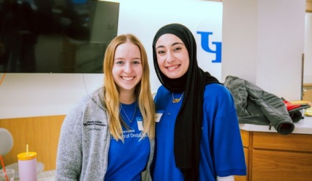 Two dental students standing in front of a teaching podicum in the preclinic simulation lab. 