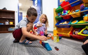 Two school aged kids playing on the floor.
