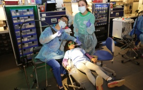 students do a free teeth cleaning on a child for Team Smile 2024. 