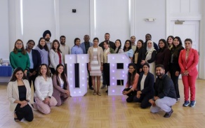 group photo of dental international dental students in business casual attire standing and kneeling inside of Harriman Hall. 