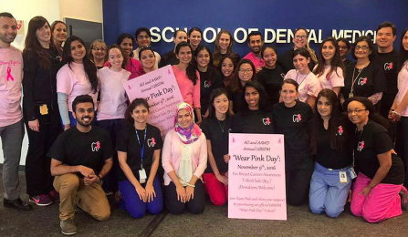 Members of AAWD club posing in rom of UB School of Dental Medicine sign. 