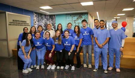 dental students standing and kneeling in our waiting area wearing blue scrubs. 
