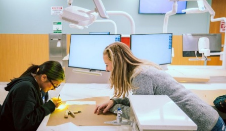 two students in the preclinic simulation lab working on a project.