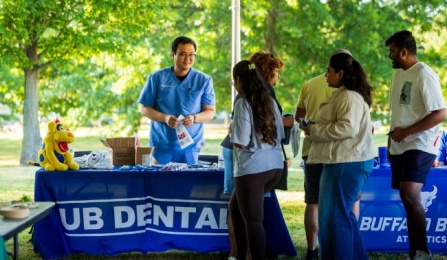 Dental Student at a table providing information to other students. 