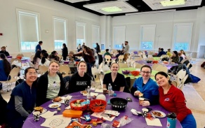Students sitting around a table in a large room. 