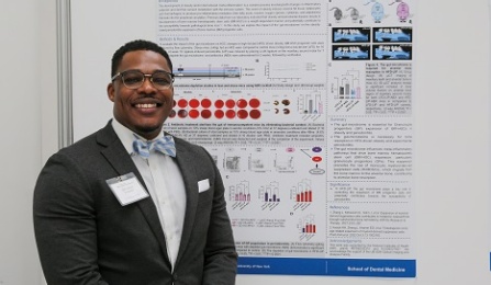 Student smiling in front of a poster presentation. 