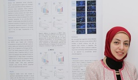 Student standing in front of research presentation poster on wall. 
