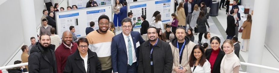 Photo of Dean and DDS students standing on stairs with research presentations behind them. 