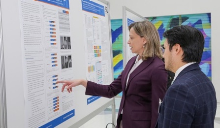 Faculty and Student standing in front of poster presentation discussing project. 