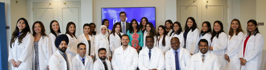 group of international dentist program student in white coats standing and kneeling. 