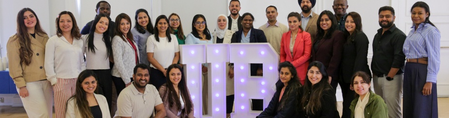 A group of International Dentist Program students posing with a light up UB.