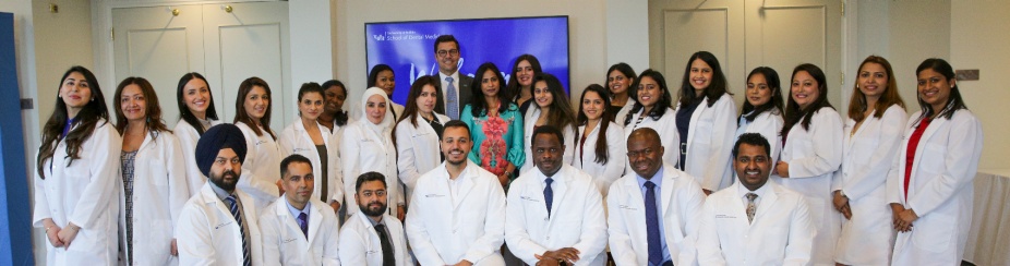 IDP students at their White Coat Ceremony pose with the dean. 