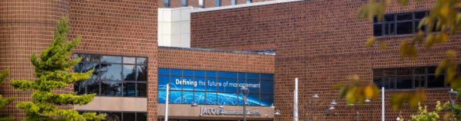 Fall colors in the trees on a sunny day on North Campus in November 2025. Hochstetter Hall appears out of focus in the background. 
