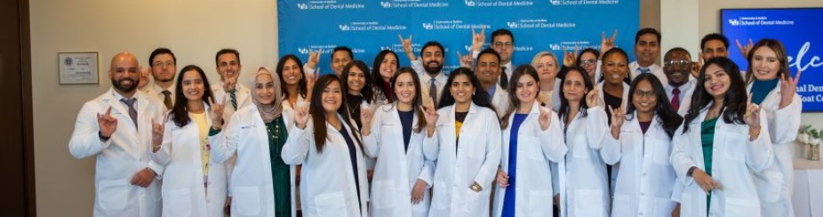 Group of new International Dentist Program students standing as a group in their white coats at the ceremony.