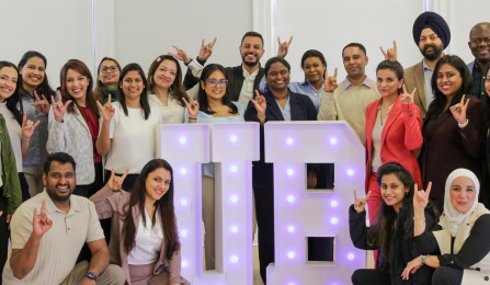 A group of IDP students surrounding a lit-up UB sign. 
