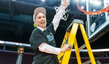 Bobby Hurley clipping a net from a basketball hoop. 