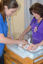 Zoom image: Nicole Raimondi (left), a junior nursing student, and Sisters Hospital nurse Cathleen Incorvia check a baby's heart rate at the maternal-newborn unit at Sisters. Photo: Carrie Sette-Camara 
