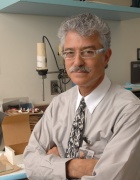 Steven Fliesler standing in shirt and tie with arms folded in lab. 