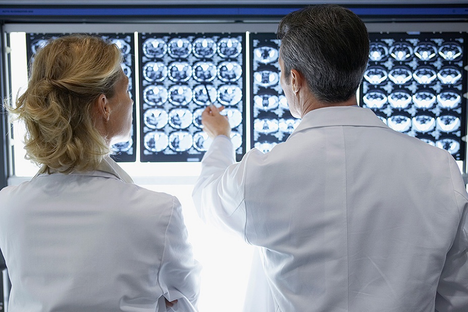 Rear view of a male and female doctor discussing brain scans in a hospital.