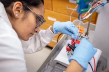 A researcher working with test tubes connected to wires. 