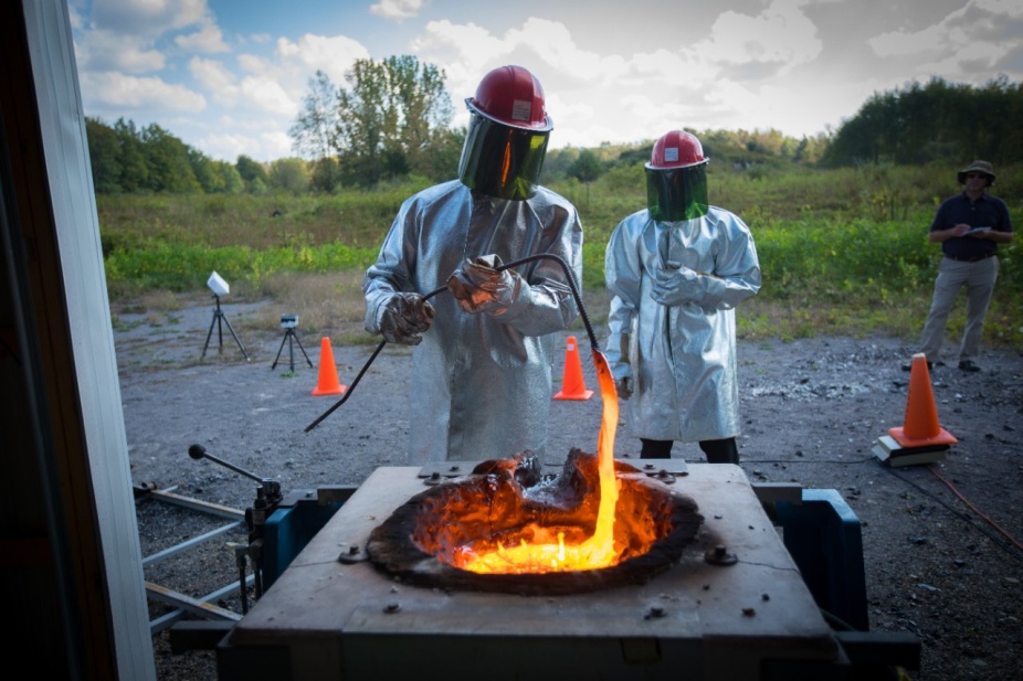 Zoom image: Ingo Sonder, a research scientist at UB&rsquo;s Center for Geohazards Studies, stirs the molten rock as it melts inside the furnace. Credit: Douglas Levere / University at Buffalo 