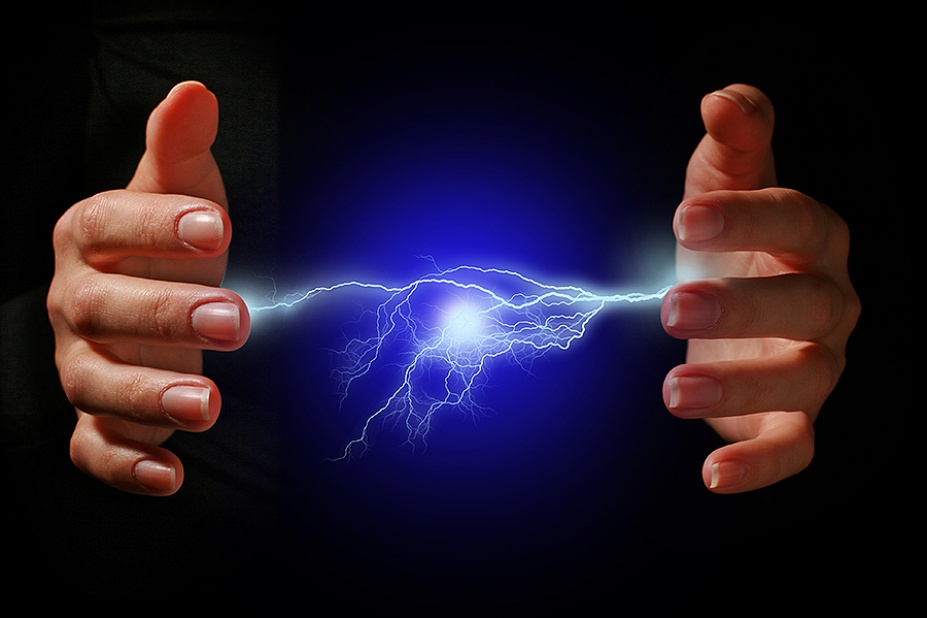 Hands and electric discharge over black background.
