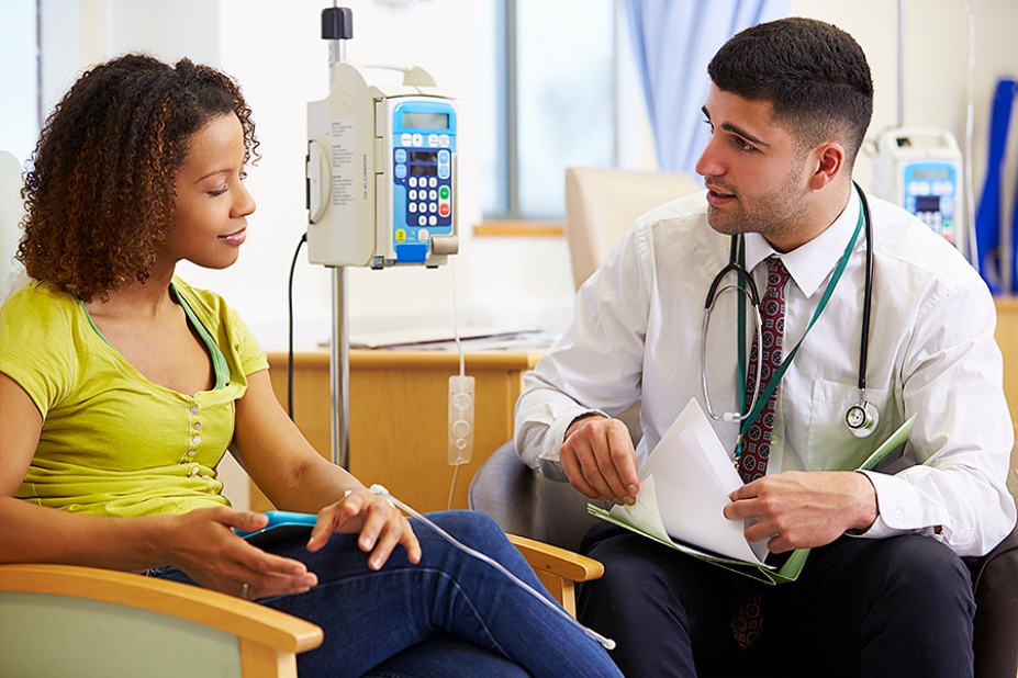 Woman undergoing chemotherapy speaking with a doctor during treatment. 