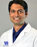 Headshot of Praveen Chandrasekharan, MD, wearing white coat with UB emblem. 