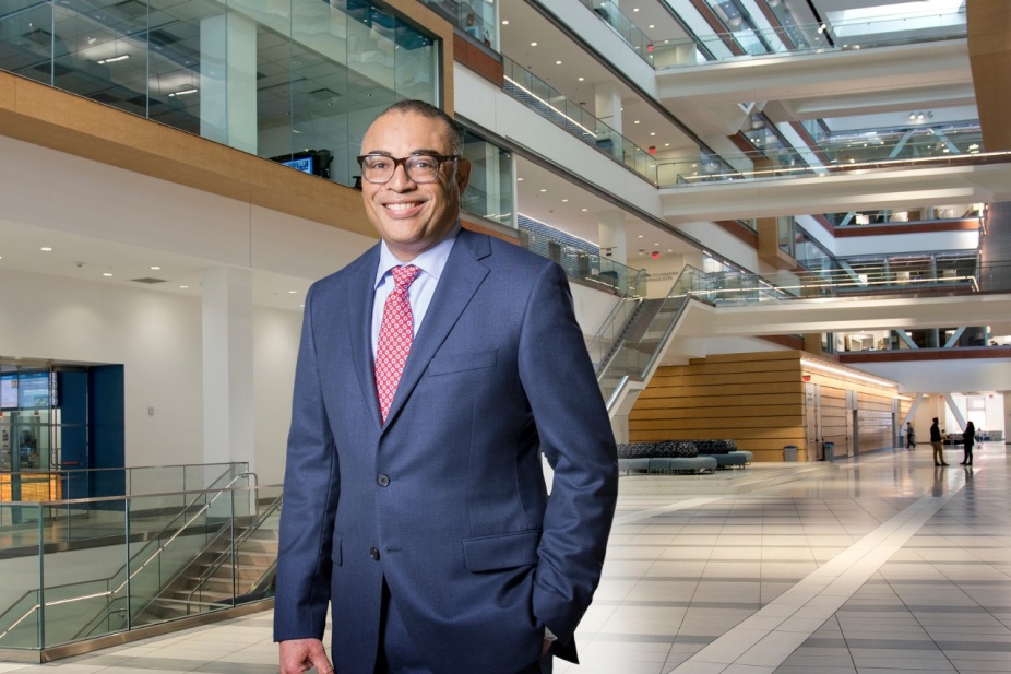 David Milling in a suit in the atrium of the Jacobs School of Medicine and Biomedical Sciences. 